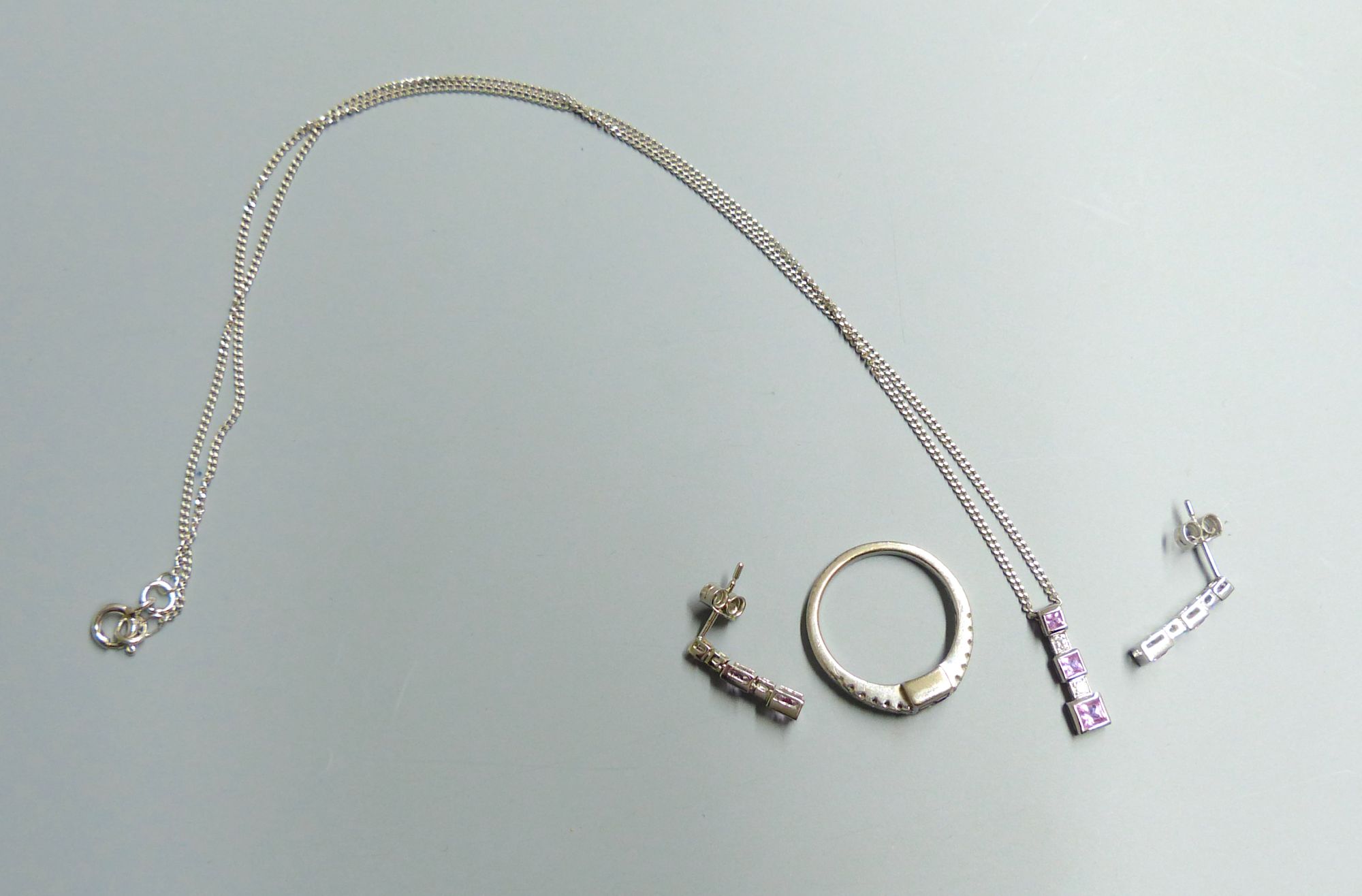 A modern 18ct white gold, pink sapphire and diamond set line pendant, on 18ct white gold chain & a pair of matching earrings